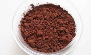 Cocoa powder is placed in a white bowl for homemade tanning lotion 