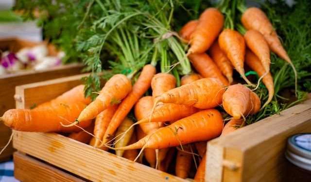 Fresh carrots in crate on wooden table