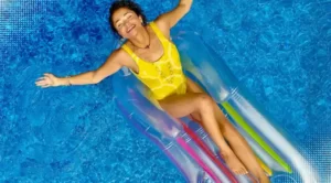 A young beautiful woman is getting tan in the swimming pool with pool floats