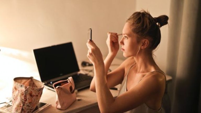 Young woman applying makeup after spray tanning at home